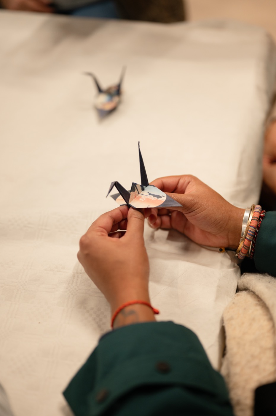 Grue en origami pliée entre les mains d'une visiteuse