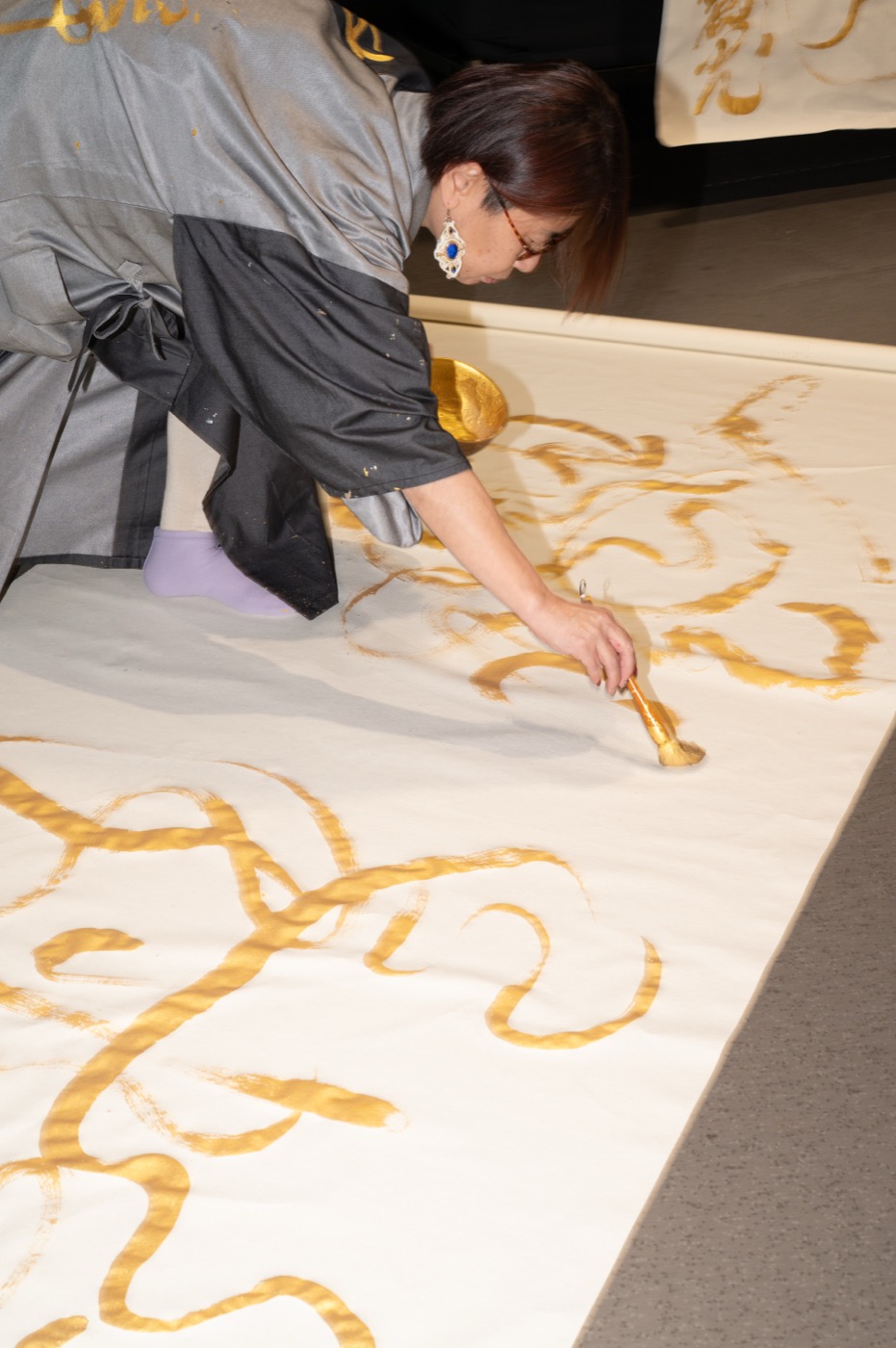 Calligraphie grand format tracée à l'encre dorée au sol